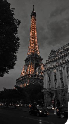 the eiffel tower lit up at night with cars parked in front of it