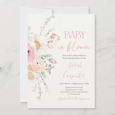 a baby in bloom card with pink flowers and greenery on the front, sitting on a marble surface