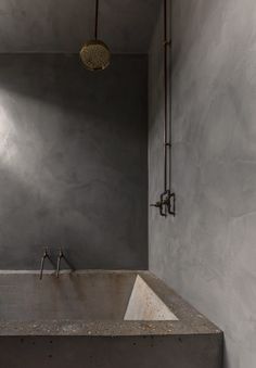 a bathroom with concrete walls and a large tub in the corner, next to a sink