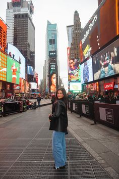 a woman standing in the middle of a street with lots of billboards on it