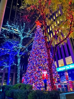 a large christmas tree in the middle of a city at night with lights on it