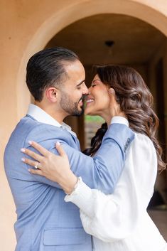 a man and woman embracing each other in front of an archway