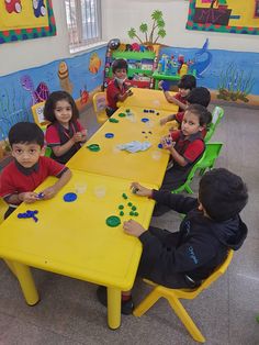 children are sitting at a table playing with magnets on the yellow plastic table top