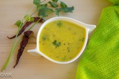 a white bowl filled with soup sitting on top of a wooden cutting board next to green napkin