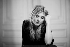 a woman sitting at a table with her hand on her head and looking over her shoulder