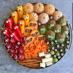 a platter filled with oranges, apples, and other fruits that have eyes on them