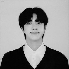 a black and white photo of a person with short hair wearing a v - neck sweater