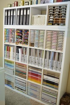 a book shelf filled with lots of books and binders on top of carpeted floor