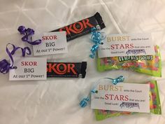 candy bar wrappers with tags on them sitting on a white sheeted bed next to blue ribbon