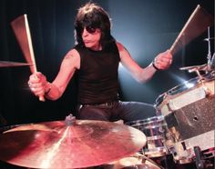 a man sitting in front of a drum set with his hands on the drumstick