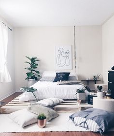 a bed room with a neatly made bed and pillows on the floor next to a window