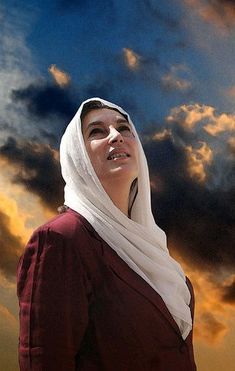 a woman wearing a headscarf is standing in front of the sky with clouds