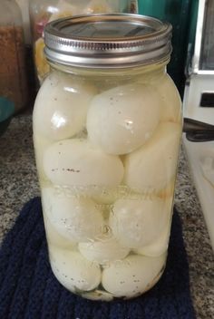 a jar filled with pickles sitting on top of a counter next to a blue towel