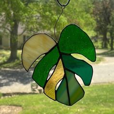 a stained glass sun catcher with a green leaf hanging from it's center piece