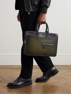 Berluti's briefcase is worth the investment. Crafted in Italy from smooth Venezia leather, it's debossed with the label's 'Scritto' calligraphy and has a zipped pocket at the front to keep your cardholder close. The structured shape is the ideal size for a tablet or portfolio. Attach the shoulder strap when navigating a busy commute. Designer Saffiano Leather Briefcase, Designer Saffiano Leather Briefcase For Formal Use, Designer Formal Bag With Engraved Logo, Designer Formal Bags With Engraved Logo, Designer Textured Leather Briefcase For Business, Designer Leather Briefcase For Business Meetings, High-end Leather Business Briefcase, High-end Leather Briefcase For Business, Luxury Briefcase With Case Included For Business Trips