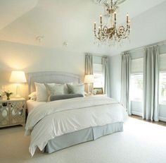 a large white bed sitting in a bedroom under a chandelier