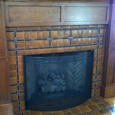 a fire place with a wooden mantle and tile