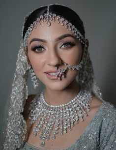 a woman wearing an elaborate head piece with pearls on her face and necklaces around her neck