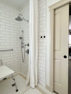 a white tiled bathroom with shower and bench