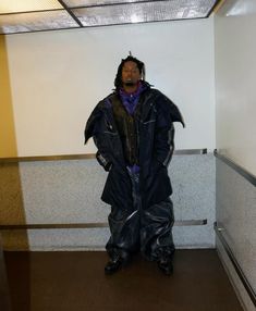 a man standing in an elevator wearing a raincoat