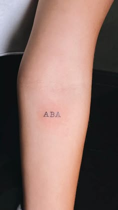 a woman's arm with the word aba tattooed on her left side ribcage