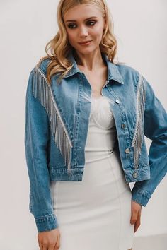 a woman in a white dress and denim jacket posing for the camera with her hands on her hips