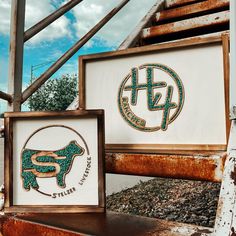 two framed signs sitting next to each other on top of a rusted metal structure