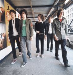 five young men standing in an underpass with their backs turned to the camera,