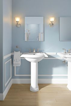 a bathroom with blue walls and two sinks in it, along with mirrors on the wall