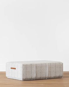 an upholstered mattress on the floor in front of a white wall and wooden floors