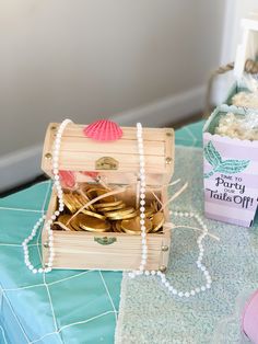 a wooden box filled with gold coins on top of a blue tablecloth covered table