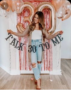 a woman standing in front of balloons with the number twenty on it