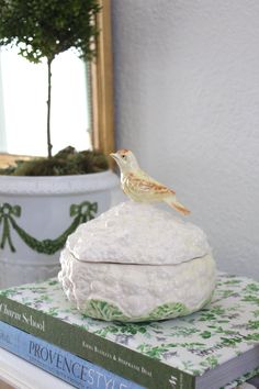 a bird figurine sitting on top of a stack of books