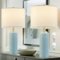 two lamps sitting on top of a table next to a mirror