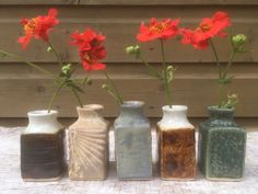 four vases with flowers in them sitting on a table