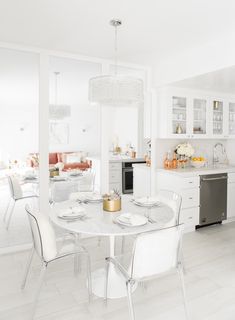 a white kitchen and dining room with glass doors open to the living area, including a table set for four