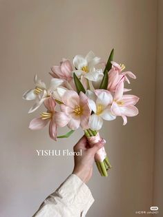 a person holding a bouquet of pink and white flowers