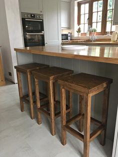 three wooden stools sitting in front of an island