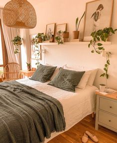 a bed sitting in a bedroom next to a window with plants on top of it