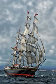 an old sailing ship in the middle of the ocean with white sails and two masts