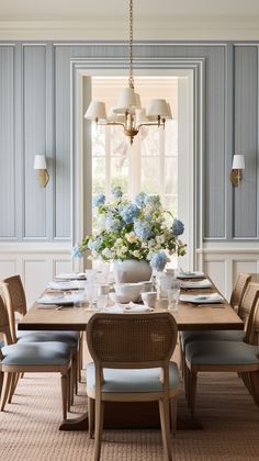 a dining room table with blue chairs and flowers in the vases on the table