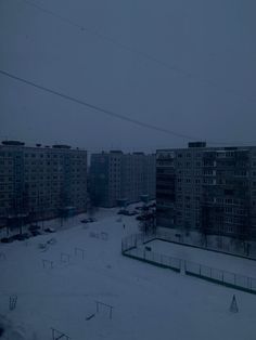 an empty hockey rink in front of apartment buildings on a snowy day with no people