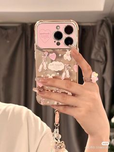 a woman holding up her phone case with hearts and animals on the back in front of her