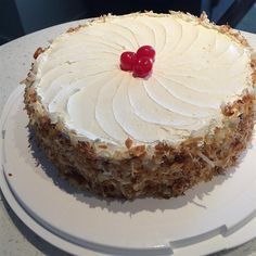 a white plate topped with a cake covered in frosting and a cherry on top