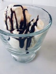 a glass bowl filled with ice cream and chocolate drizzled on the top