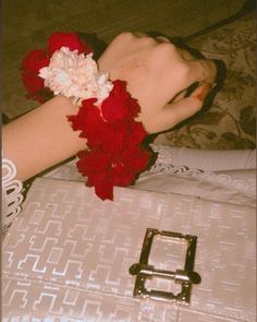 a woman's arm with red flowers on it and a metal buckle around her wrist