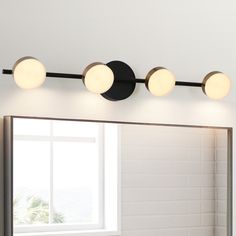 a bathroom mirror with three lights on it and a window in the backround