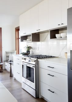 a kitchen with white cabinets and stainless steel appliances