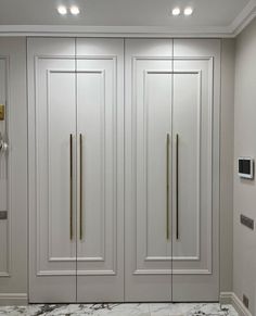 a white closet with marble flooring and gold handles on the doors, in an empty room