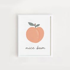 an orange with the words nice bum on it is mounted in a white frame against a wall